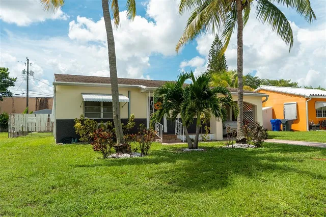 a view of a house with a yard and palm trees