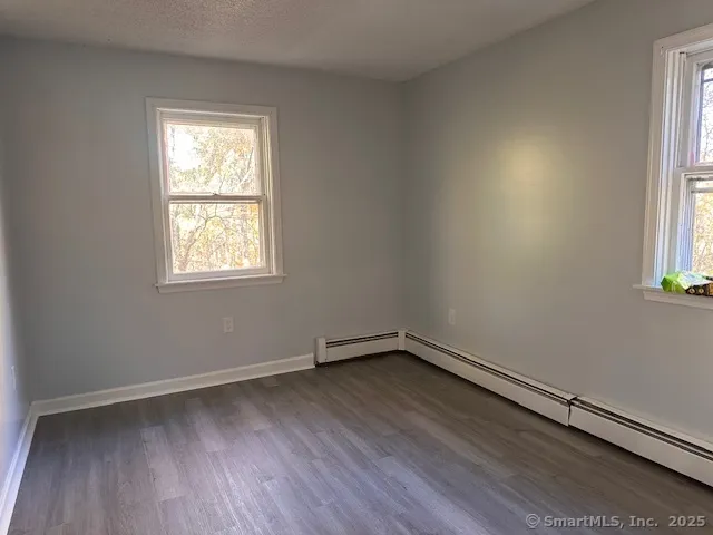 an empty room with wooden floor and a hallway