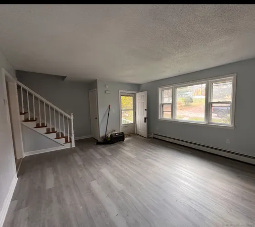 a view of an empty room with wooden floor and windows