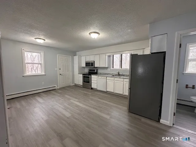 a view of a kitchen with a refrigerator a stove top oven and cabinets