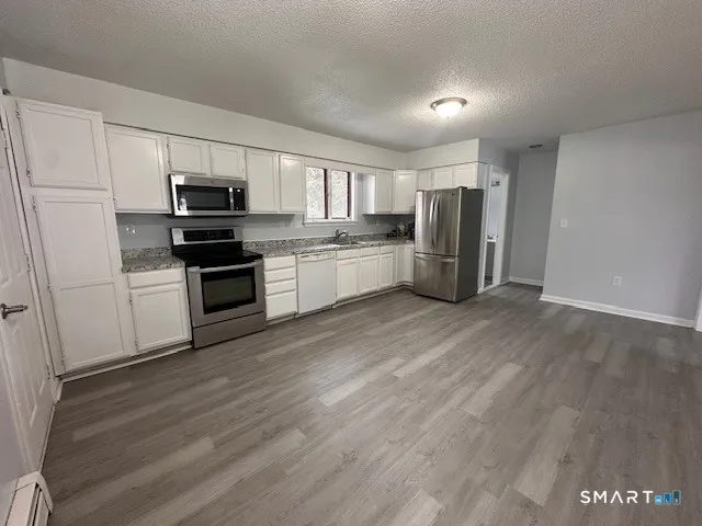 an empty room with wooden floor fireplace and windows
