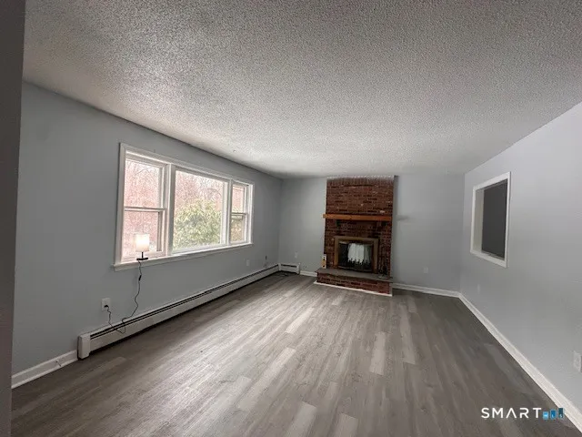 an empty room with wooden floor fireplace and windows
