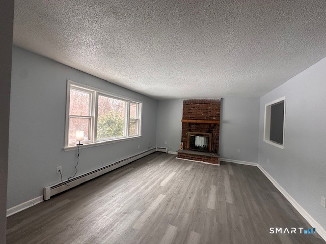 259 Westchester Road, Unit A Colchester, CT 06415 - Photo 5 of 24 an empty room with wooden floor fireplace and windows