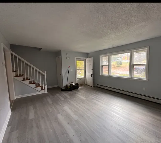 a view of an empty room with wooden floor and windows
