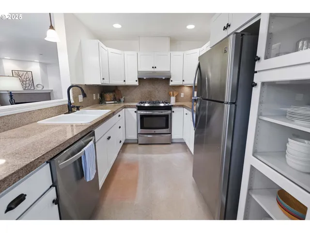 a kitchen with stainless steel appliances granite countertop a refrigerator a sink a stove and white cabinets with wooden floor