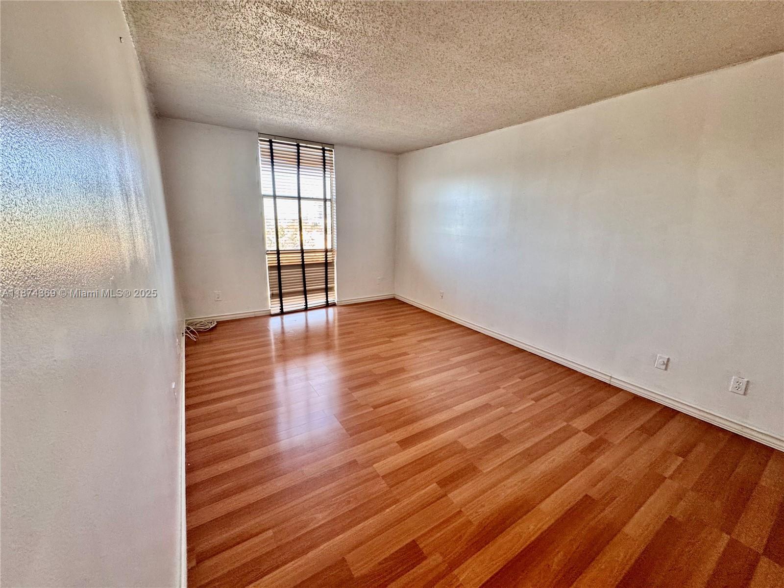 13499 Biscayne Boulevard, Unit 703 North Miami, FL 33181 - Photo 10 of 22 a view of an empty room with wooden floor and a window