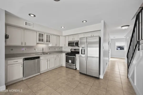 a kitchen with granite countertop white cabinets sink and stainless steel appliances