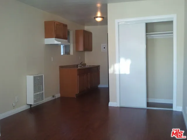 an empty room with wooden floor cabinet and windows