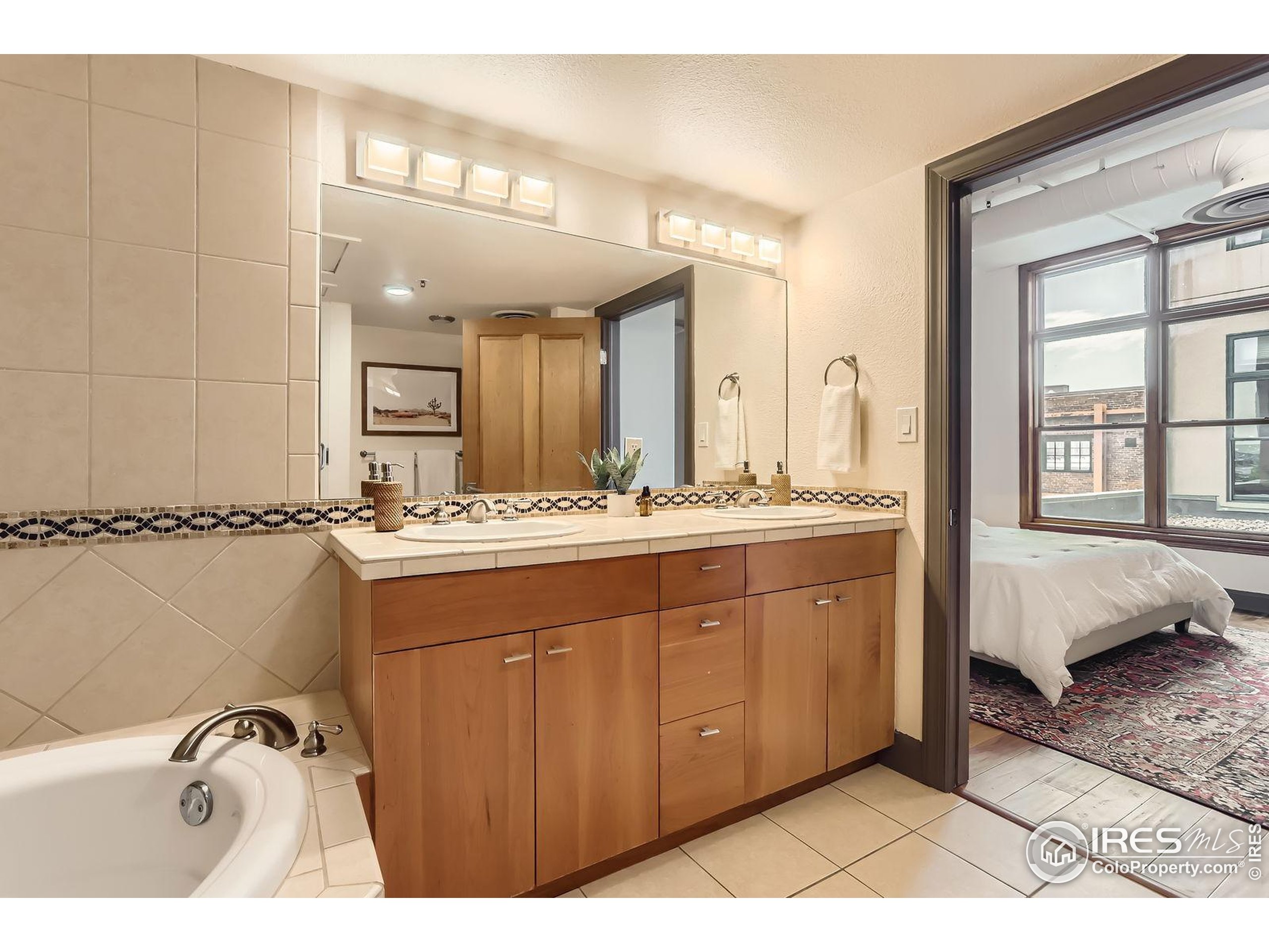 2245 Blake Street, Unit D Denver, CO 80205 - Photo 9 of 36 a spacious bathroom with a double vanity sink a mirror and a bathtub
