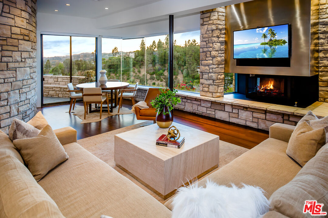 1131 Miradero Road Beverly Hills, CA 90210 - Photo 11 of 42 a living room with furniture a flat screen tv and a floor to ceiling window