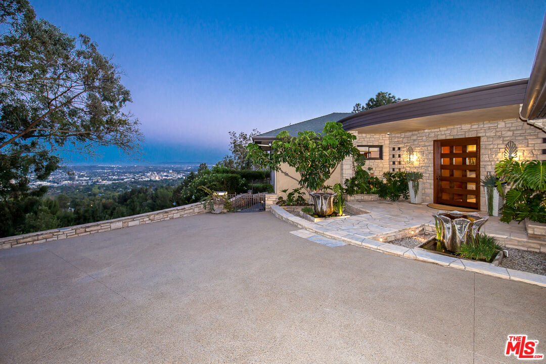 1131 Miradero Road Beverly Hills, CA 90210 - Photo 2 of 42 a view of a patio with a table and chairs under an umbrella