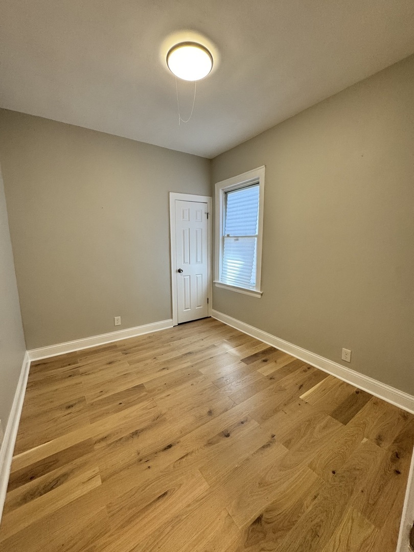 822 East 87th Place Chicago, IL 60619 - Photo 15 of 31 an empty room with wooden floor and windows