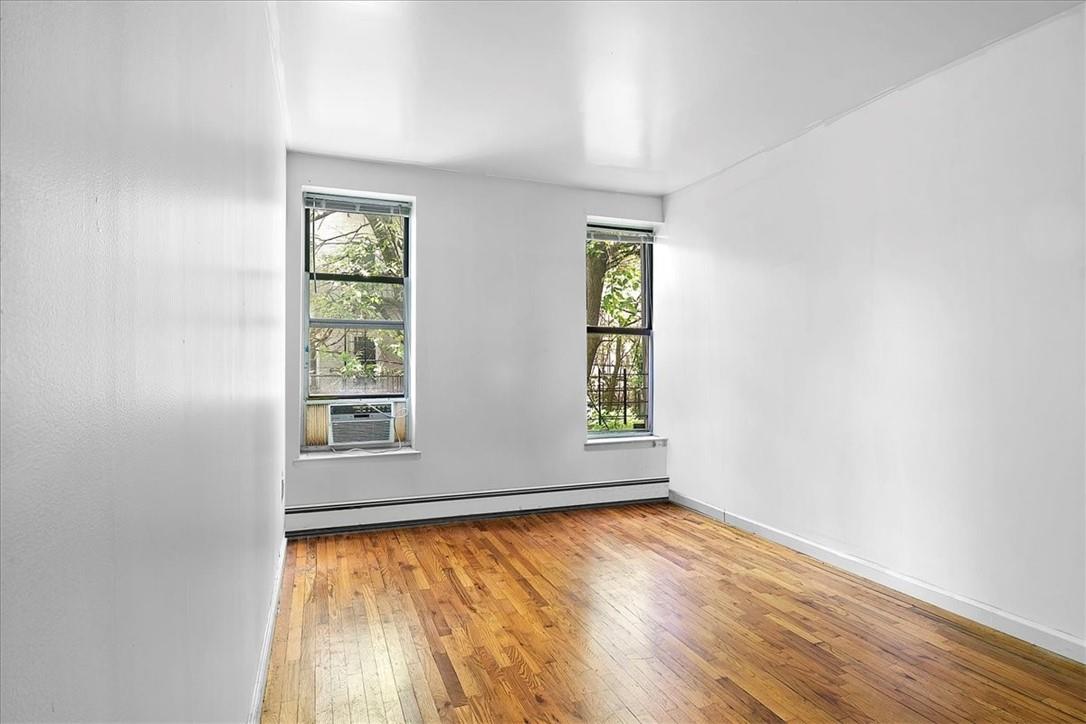 1012 Faile Street, Unit 1012A Bronx, NY 10459 - Photo 14 of 20 an empty room with wooden floor and windows
