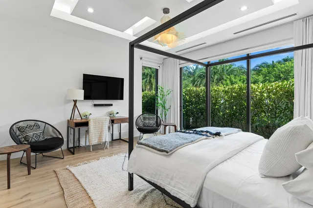 a bedroom with a bed a window and a flat screen tv