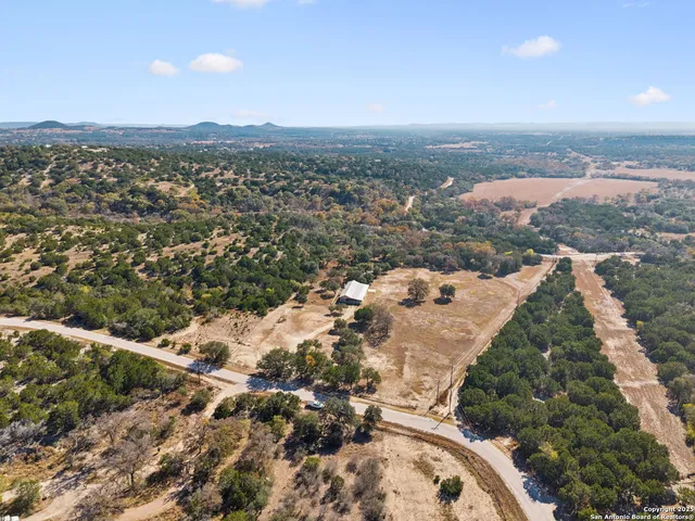 an aerial view of residential houses with outdoor space and trees
