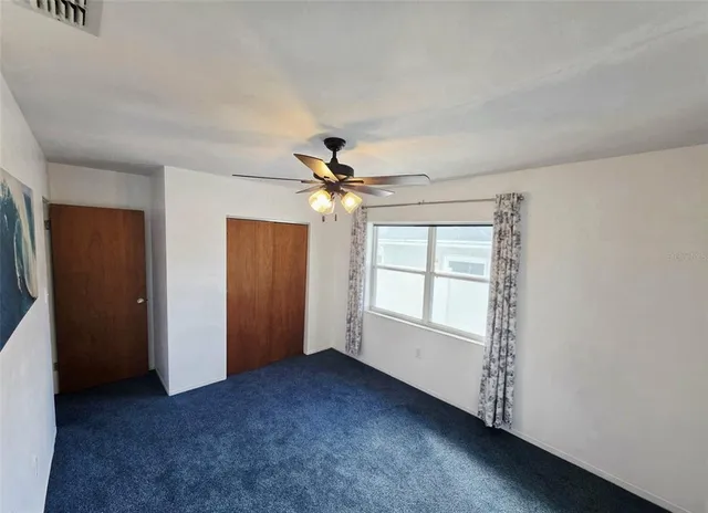 an empty room with windows and fan