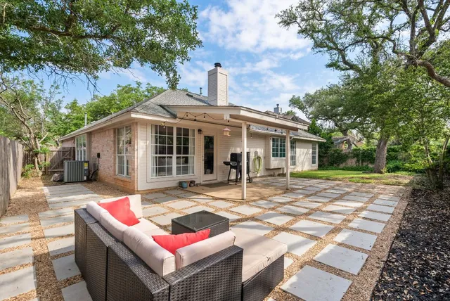 a view of a patio with a table and chairs under an umbrella with large trees