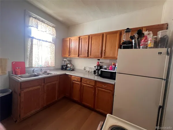 a white kitchen with sink refrigerator and window