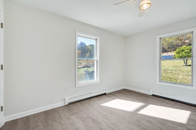 an empty room with wooden floor cabinet and windows