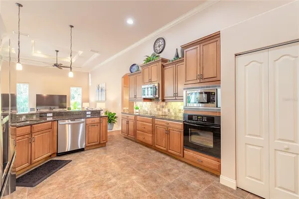 a kitchen with stainless steel appliances granite countertop a stove top oven a sink dishwasher a dining table and chairs with wooden floor