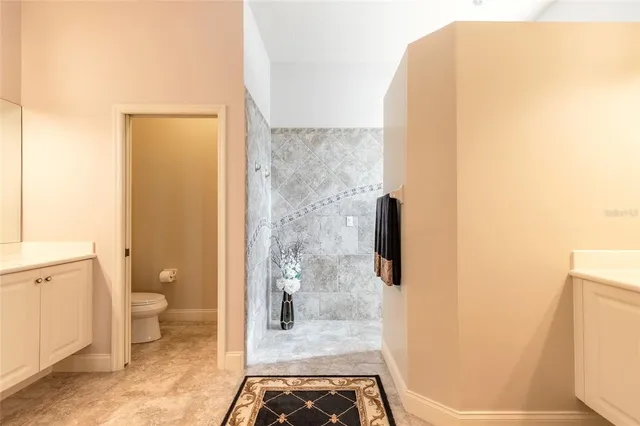 a spacious bathroom with a granite countertop sink a toilet and a mirror