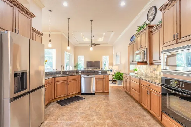 a large kitchen with stainless steel appliances granite countertop a stove a sink dishwasher and a refrigerator with wooden floor