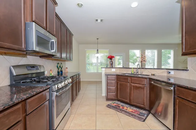 a kitchen with stainless steel appliances granite countertop a stove microwave and cabinets