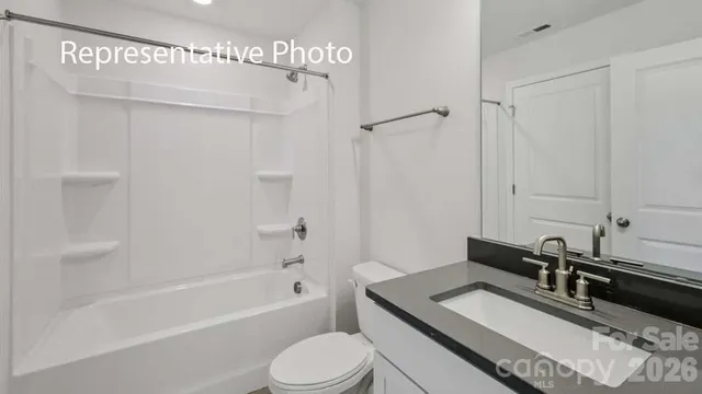 a bathroom with a granite countertop sink a toilet a mirror and shower