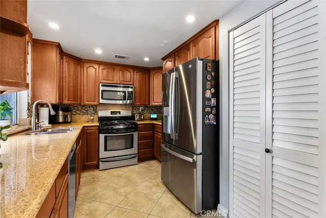 a kitchen with stainless steel appliances granite countertop a refrigerator a stove a sink and a microwave