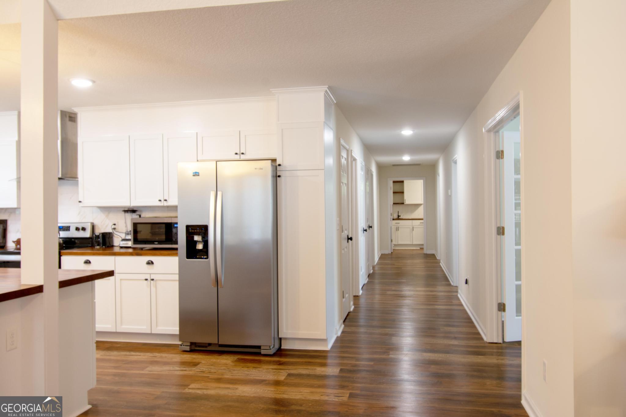 149 Main Street Rocky Ford, GA 30455 - Photo 32 of 44 a view of a kitchen with a refrigerator a stove top oven and wooden floor