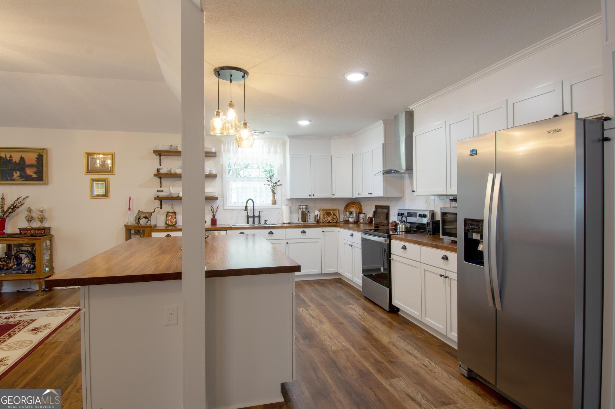 149 Main Street Rocky Ford, GA 30455 - Photo 8 of 44 a kitchen with stainless steel appliances granite countertop a refrigerator a sink dishwasher a stove and white countertops with wooden floor