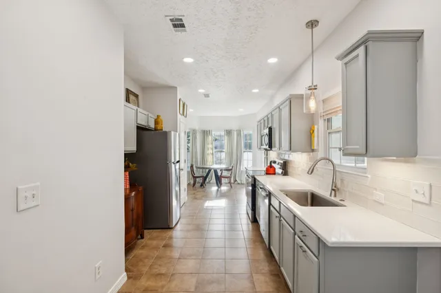 a large white kitchen with a large window and refrigerator