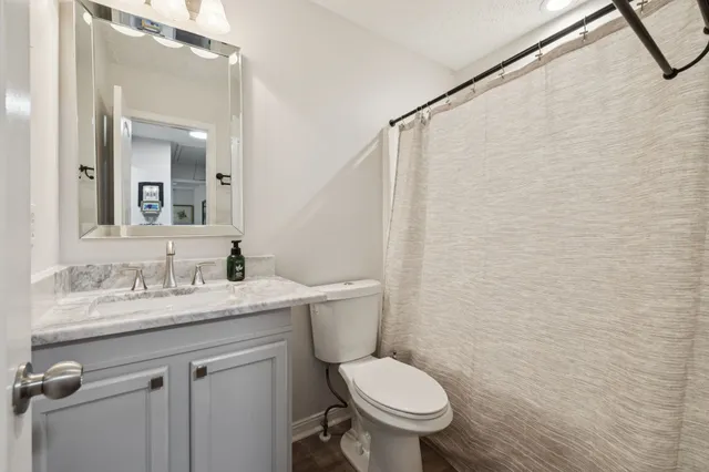 a bathroom with a granite countertop sink toilet and a mirror