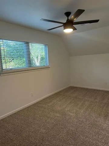 an empty room with a window and a ceiling fan