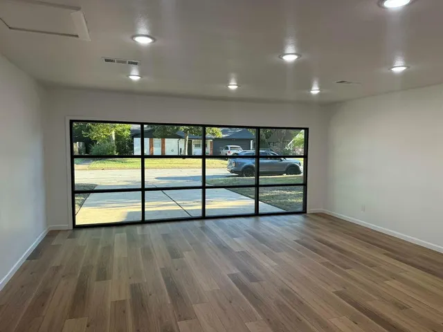 a view of an empty room with wooden floor and windows
