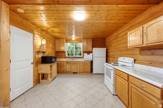 2640 East Weber Canyon Road Oakley, UT 84055 - Photo 54 of 56 Wood-paneled walls and ceiling, full-height cabinetry, window above the sink, white appliances, and tile flooring