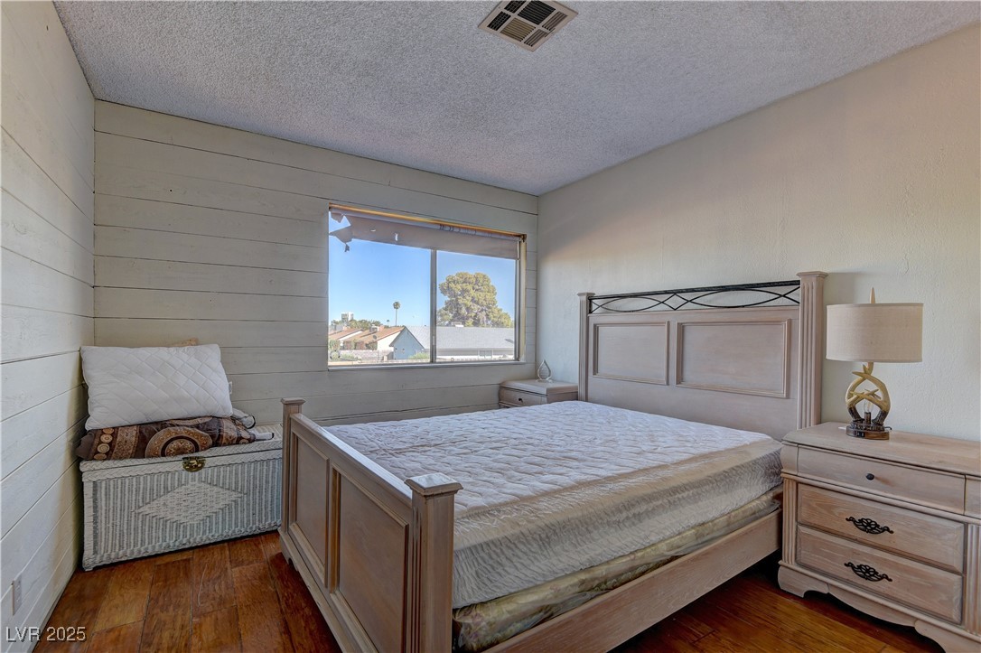 3751 El Camino Road Las Vegas, NV 89103 - Photo 22 of 27 Bedroom with wood finished floors, a textured ceiling, and wood walls