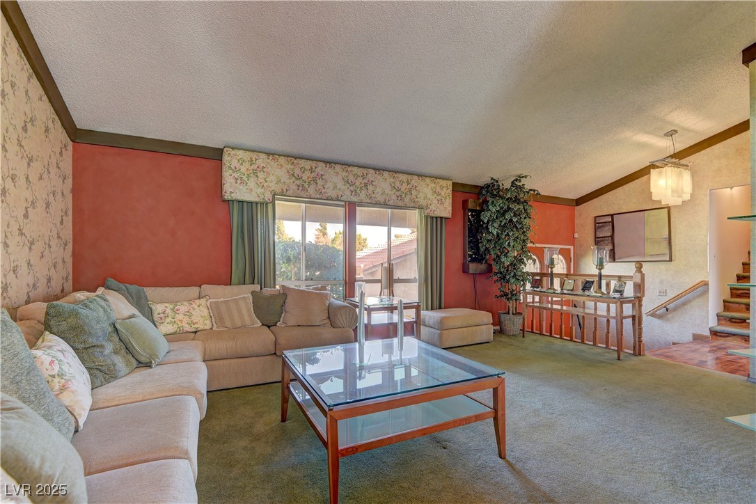 3751 El Camino Road Las Vegas, NV 89103 - Photo 7 of 27 Carpeted living area featuring a textured ceiling, lofted ceiling, crown molding, and wallpapered walls