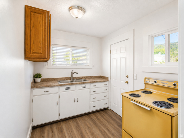 69 South Main Street Manti, UT 84642 - Photo 24 of 44 Kitchen featuring a double basin stainless steel sink, wood-finish flooring, white cabinetry, and a countertop with a textured finish