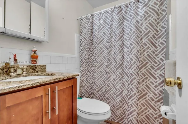a bathroom with a granite countertop toilet sink and mirror