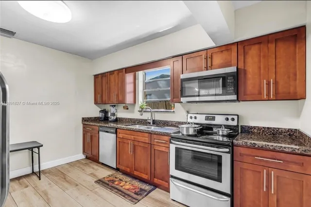 a kitchen with stainless steel appliances a stove sink microwave and cabinets