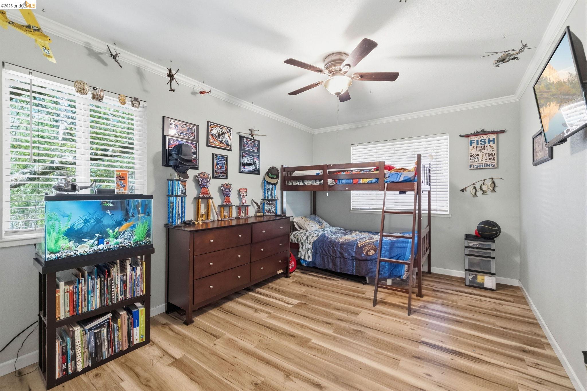 19059 Raboul Court Groveland, CA 95321 - Photo 14 of 21 Interior room featuring wood-finish flooring, two large windows with blinds, a ceiling fan with integrated lighting, and crown molding
