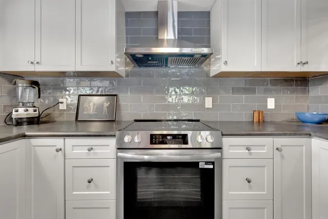 a kitchen with granite countertop white cabinets and a stove