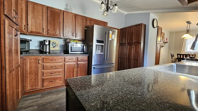 a kitchen with stainless steel appliances granite countertop a refrigerator a stove and a sink with cabinets