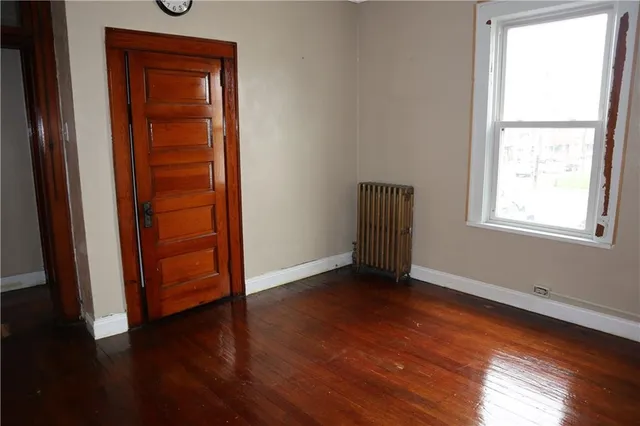 an empty room with wooden floor closet and windows