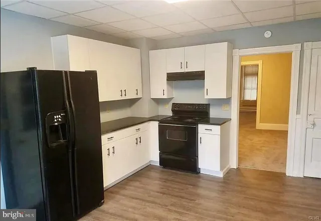a kitchen with granite countertop a refrigerator and a stove top oven
