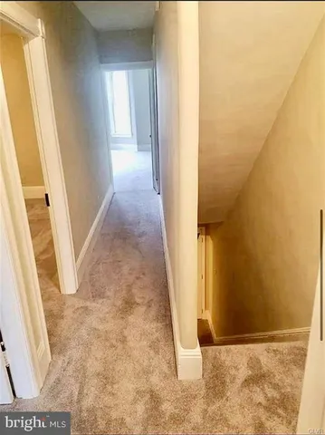 a view of a hallway with wooden floor and a bathroom