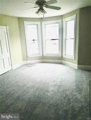 an empty room with a ceiling fan and window