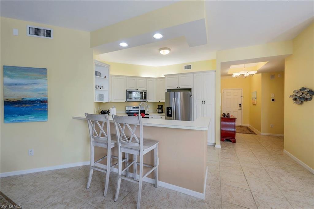 460 Launch Circle, Unit 301 Naples, FL 34108 - Photo 4 of 28 a kitchen with a dining table chairs and white cabinets