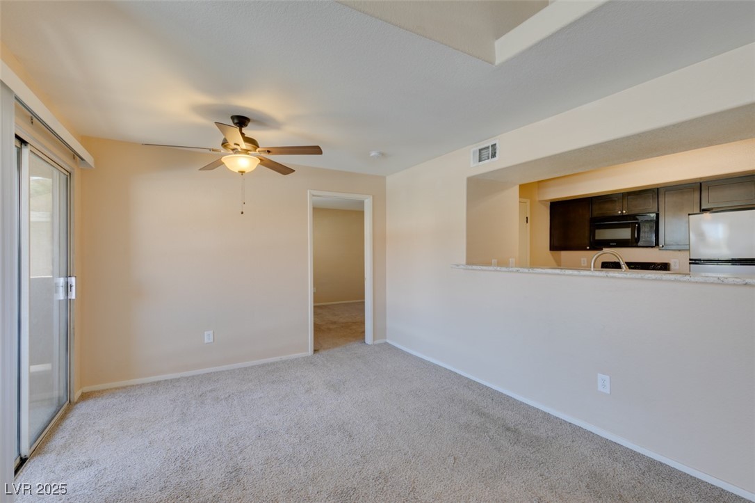 2300 East Silverado Ranch Boulevard, Unit 2190 Las Vegas, NV 89123 - Photo 21 of 41 Unfurnished living room with light carpet and a ceiling fan